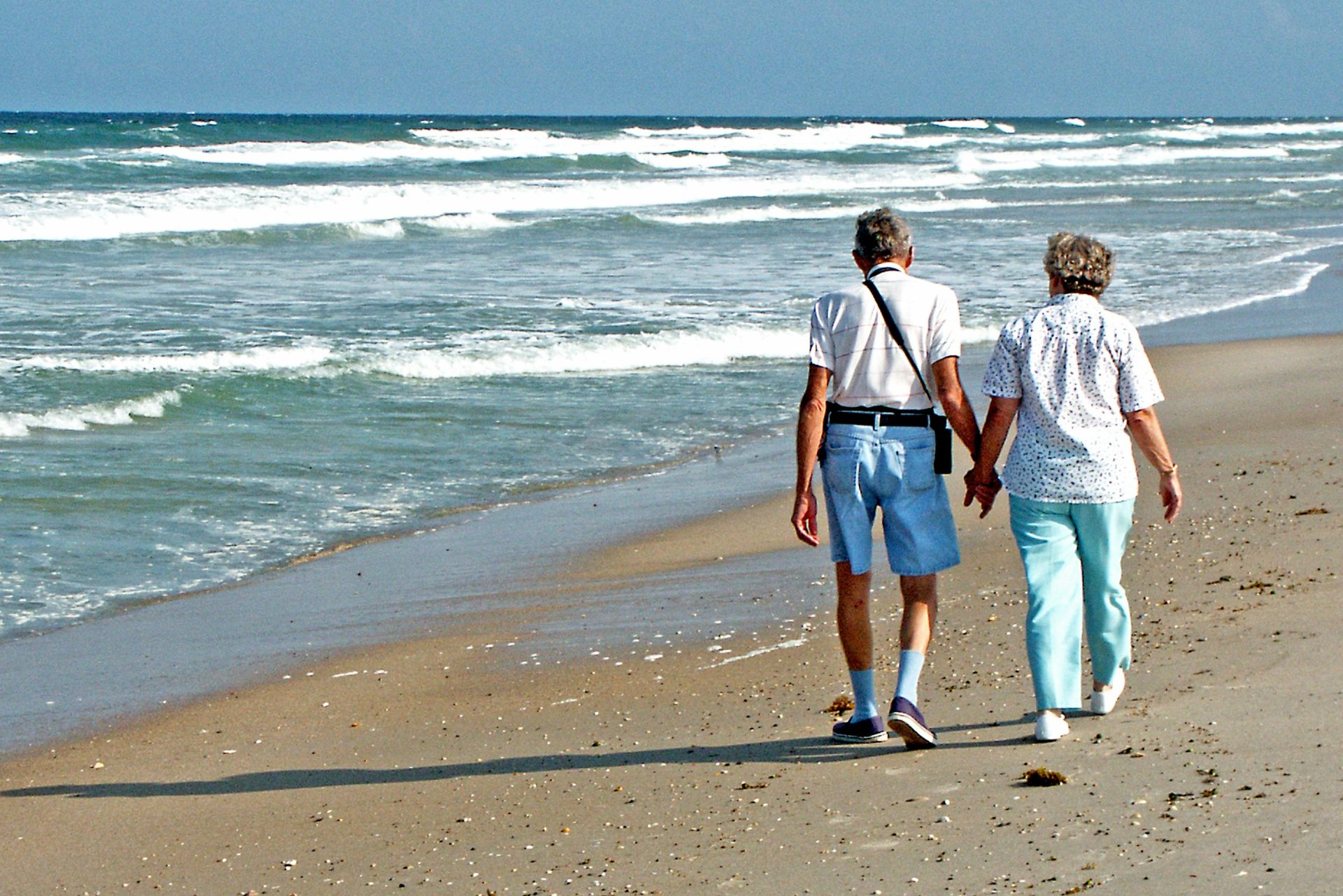 Couple walks hand-in-hand on the beach.